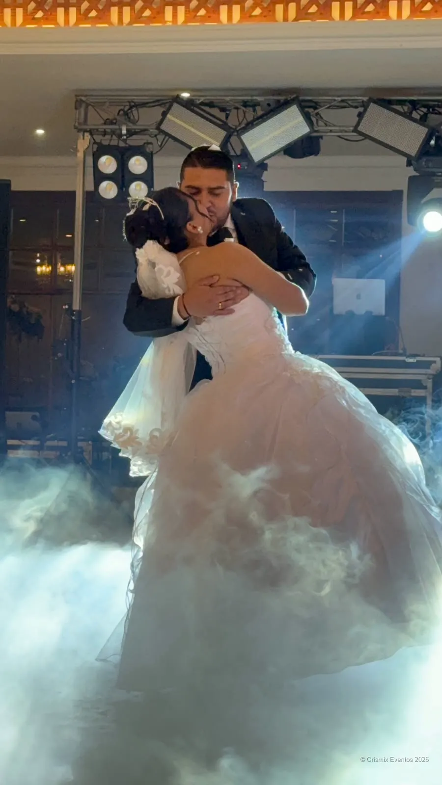 Novios bailando sobre humo bajo en una celebración real.